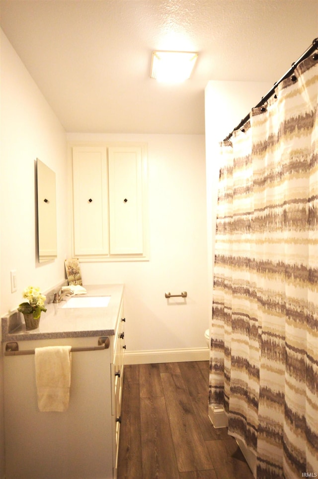 bathroom with wood-type flooring, toilet, a textured ceiling, and vanity