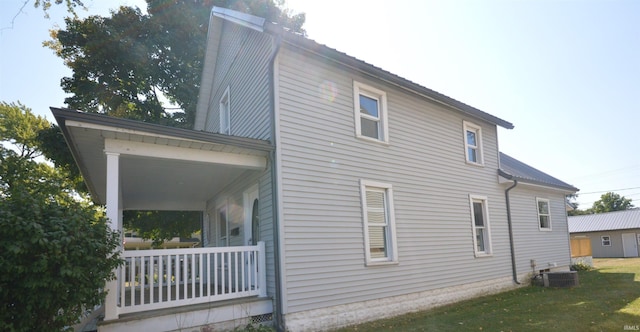 view of home's exterior with a lawn, a porch, and central AC