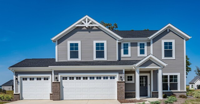 view of front of house featuring a shingled roof, an attached garage, brick siding, and concrete driveway