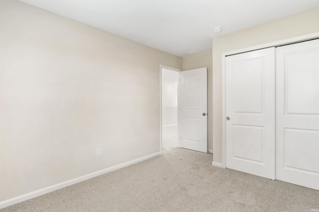 unfurnished bedroom with light carpet and a closet