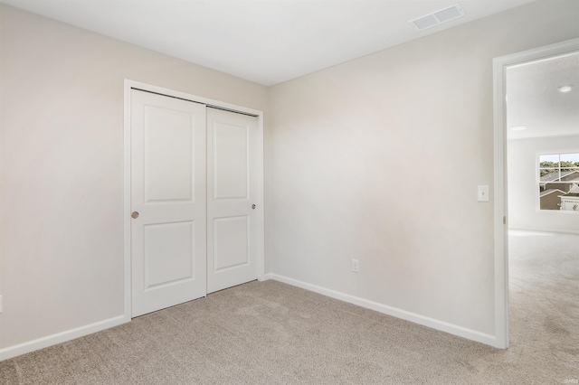 unfurnished bedroom with a closet and light carpet