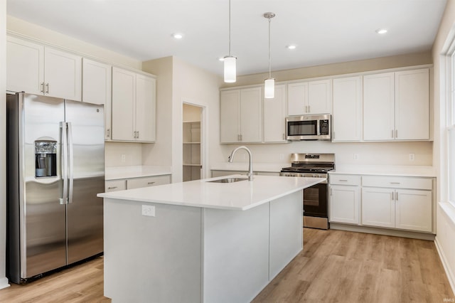 kitchen featuring appliances with stainless steel finishes, an island with sink, light hardwood / wood-style flooring, and sink