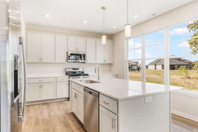 kitchen featuring a wealth of natural light, an island with sink, sink, and appliances with stainless steel finishes