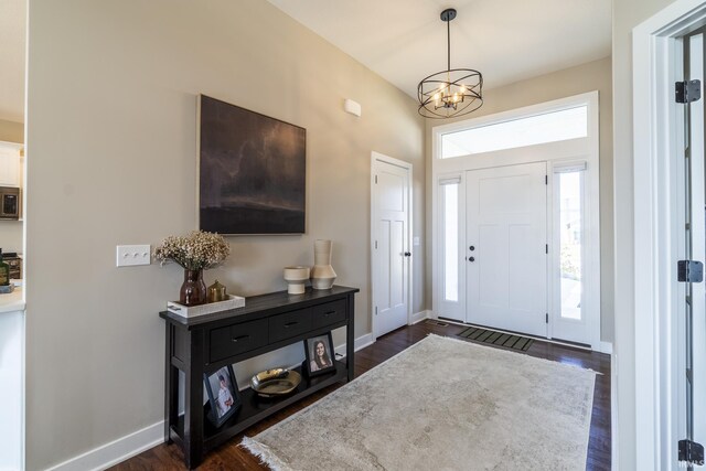 foyer featuring dark wood finished floors, a notable chandelier, and baseboards