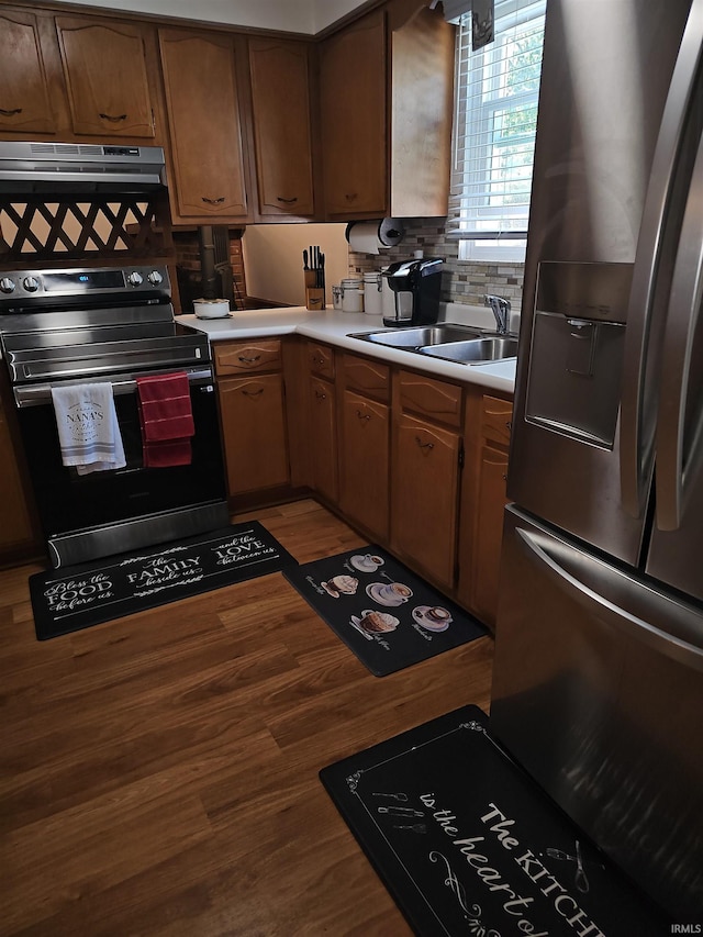 kitchen featuring hardwood / wood-style flooring, stainless steel appliances, sink, extractor fan, and decorative backsplash