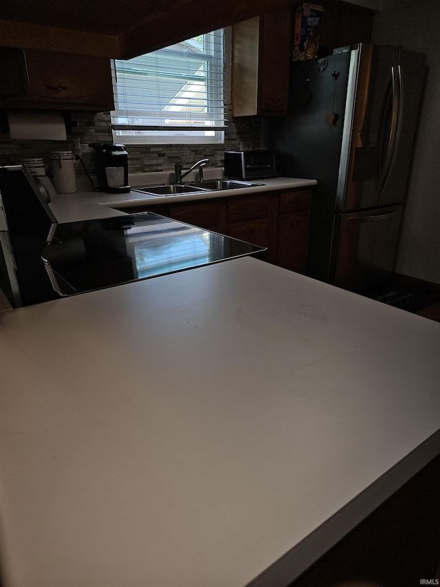 kitchen featuring range, sink, stainless steel fridge, and decorative backsplash