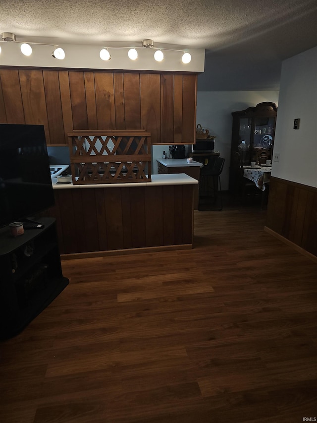 kitchen featuring a textured ceiling, dark hardwood / wood-style flooring, and wooden walls