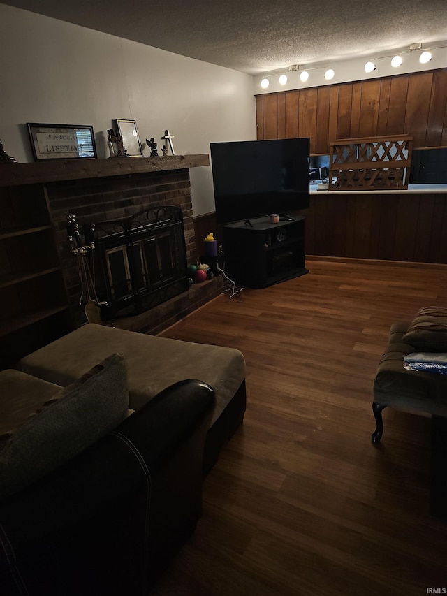 living room with a fireplace, a textured ceiling, and dark hardwood / wood-style floors