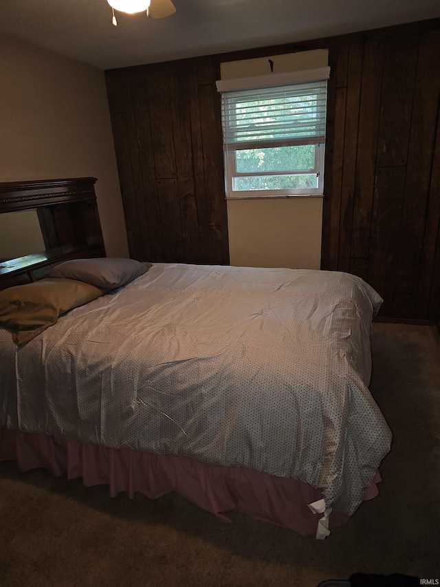 bedroom featuring carpet flooring, wood walls, and ceiling fan