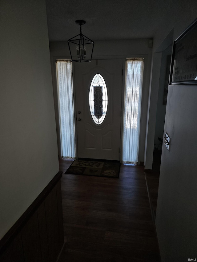 entryway with dark hardwood / wood-style flooring and a notable chandelier