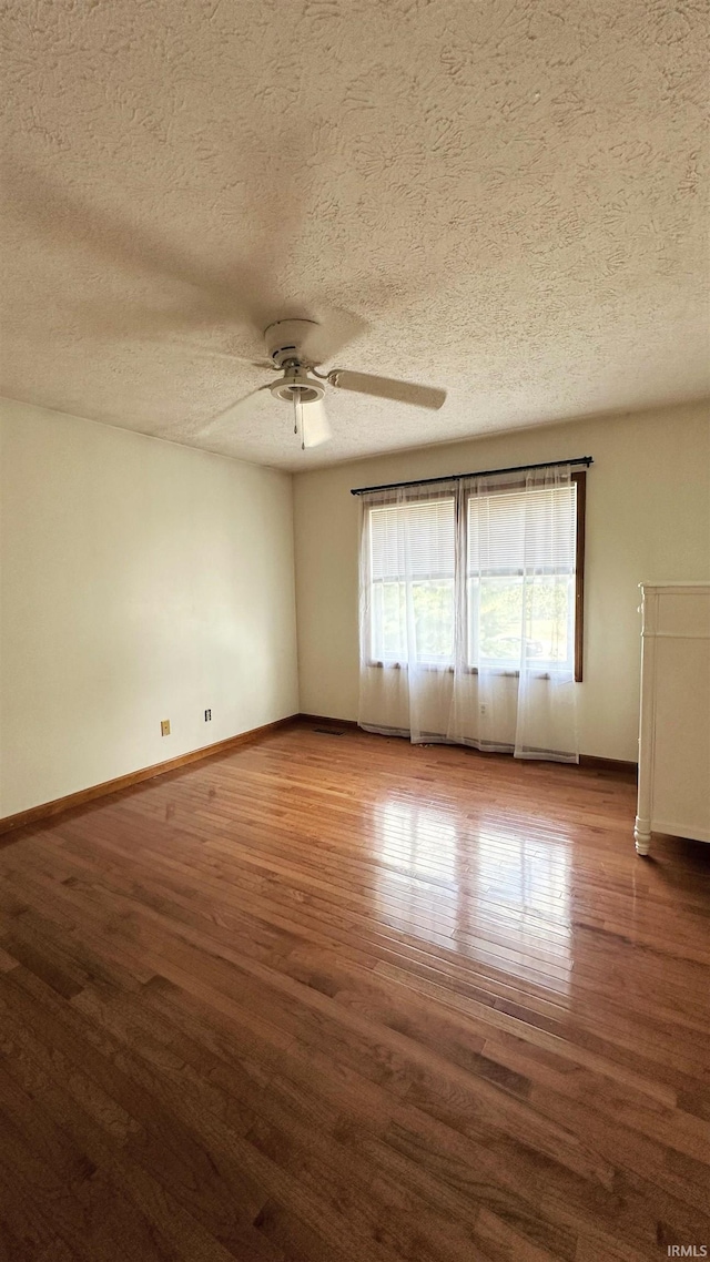 empty room with ceiling fan, hardwood / wood-style floors, and a textured ceiling