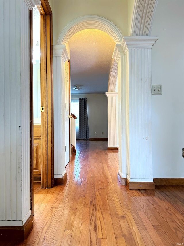 corridor featuring light wood-type flooring, a textured ceiling, and wooden walls