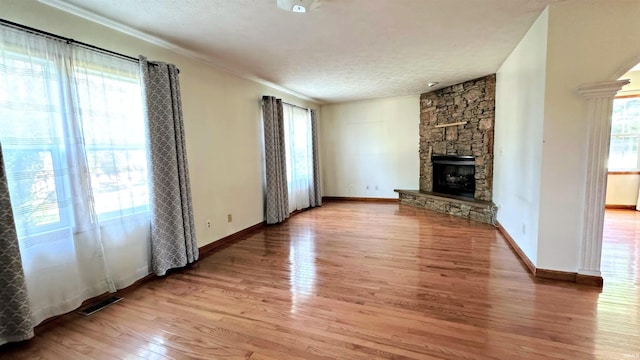 unfurnished living room featuring a textured ceiling, light wood-type flooring, a fireplace, and a healthy amount of sunlight