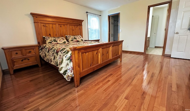 bedroom with light hardwood / wood-style flooring and a walk in closet