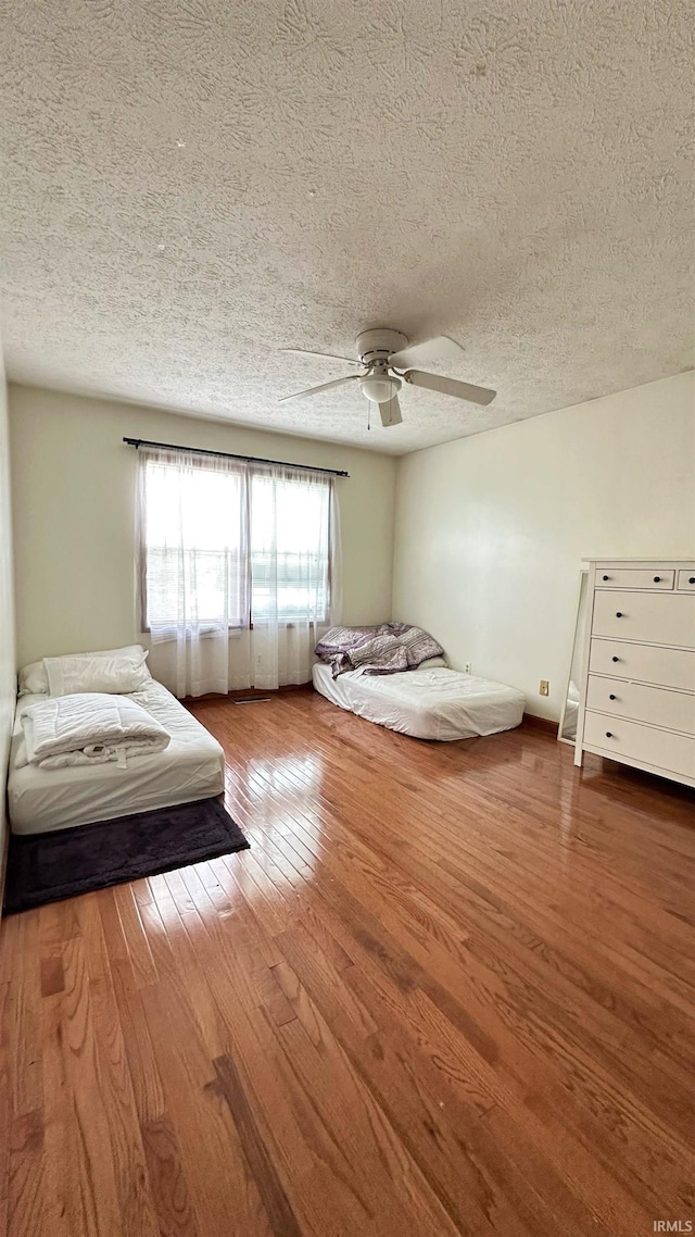 unfurnished bedroom with ceiling fan, hardwood / wood-style flooring, and a textured ceiling