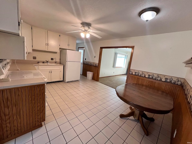 kitchen featuring white cabinets, white appliances, sink, ceiling fan, and a textured ceiling