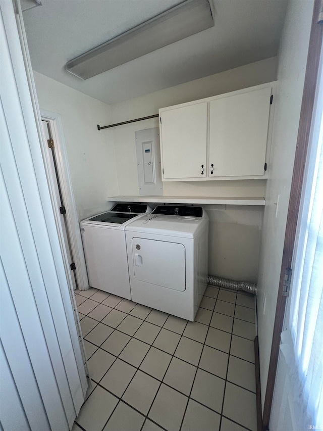 washroom featuring light tile patterned floors, washing machine and clothes dryer, cabinets, and electric panel