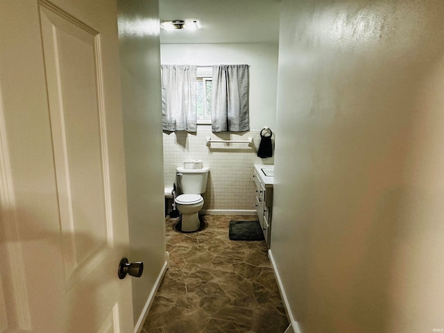 bathroom featuring tile walls, vanity, and toilet