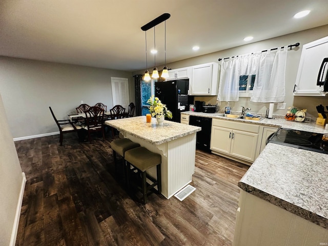 kitchen with black appliances, a center island, dark wood-type flooring, pendant lighting, and white cabinetry