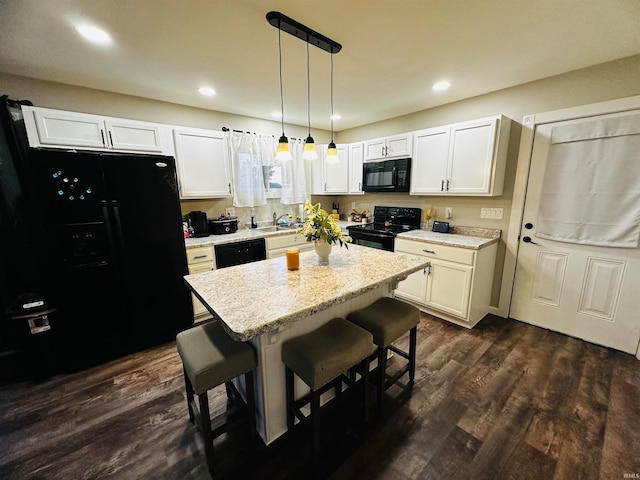 kitchen featuring pendant lighting, white cabinets, dark wood-type flooring, black appliances, and a kitchen bar