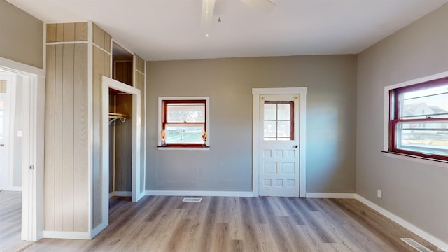 unfurnished bedroom with ceiling fan, light wood-type flooring, and multiple windows