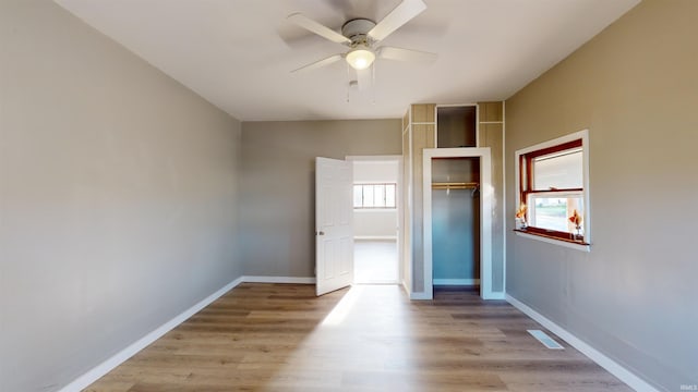 unfurnished bedroom with light hardwood / wood-style flooring, ceiling fan, and multiple windows