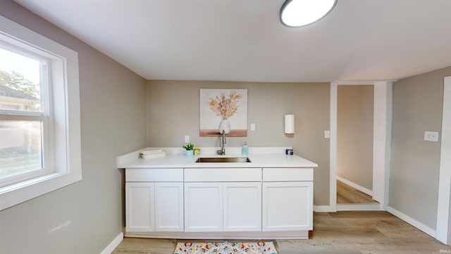 kitchen with a healthy amount of sunlight, light hardwood / wood-style flooring, sink, and white cabinets