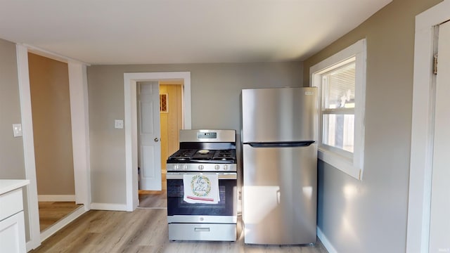 kitchen featuring light wood-type flooring, appliances with stainless steel finishes, and white cabinets