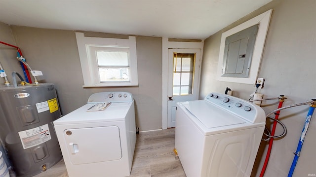 clothes washing area featuring electric panel, light hardwood / wood-style floors, separate washer and dryer, and water heater