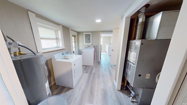 clothes washing area featuring light wood-type flooring, electric water heater, washer and dryer, and electric panel