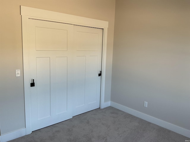 unfurnished bedroom featuring light carpet and a closet