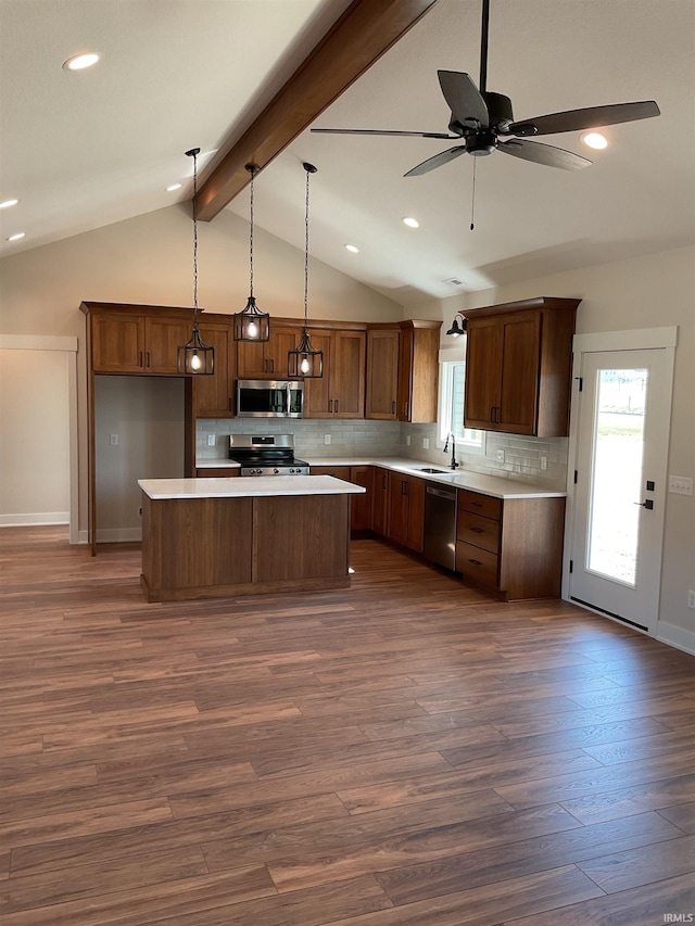 kitchen featuring ceiling fan, vaulted ceiling with beams, appliances with stainless steel finishes, dark hardwood / wood-style floors, and a center island