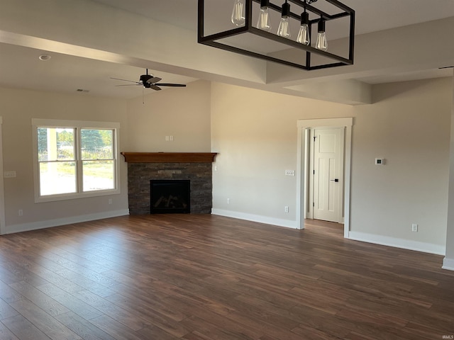 unfurnished living room featuring ceiling fan, a stone fireplace, and dark hardwood / wood-style flooring