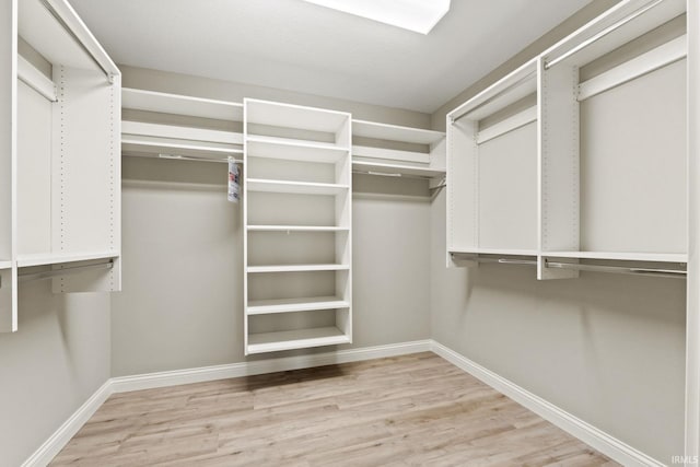 walk in closet with light hardwood / wood-style flooring