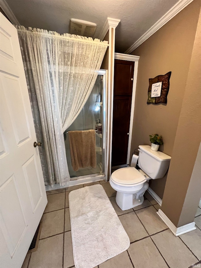 bathroom with tile patterned flooring, a textured ceiling, crown molding, toilet, and a shower with door