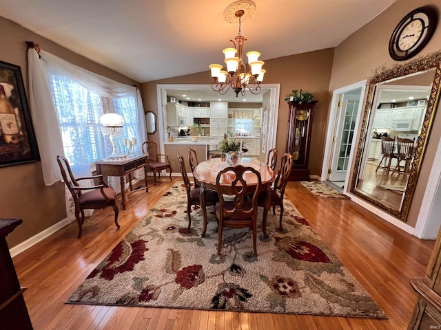 dining space with wood-type flooring, a notable chandelier, and lofted ceiling