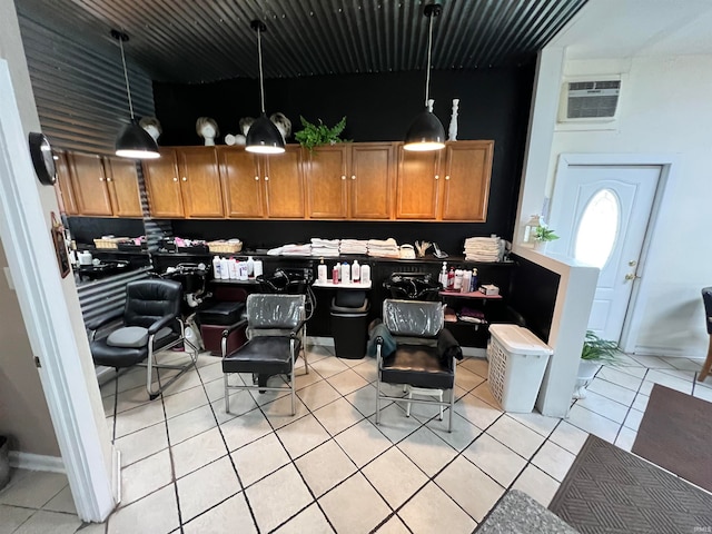 kitchen with an AC wall unit, light tile patterned floors, and decorative light fixtures