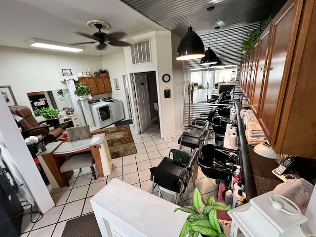 interior space with ceiling fan, pendant lighting, light tile patterned flooring, and washing machine and dryer