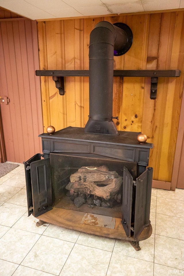 details featuring wood walls, a wood stove, and tile patterned floors