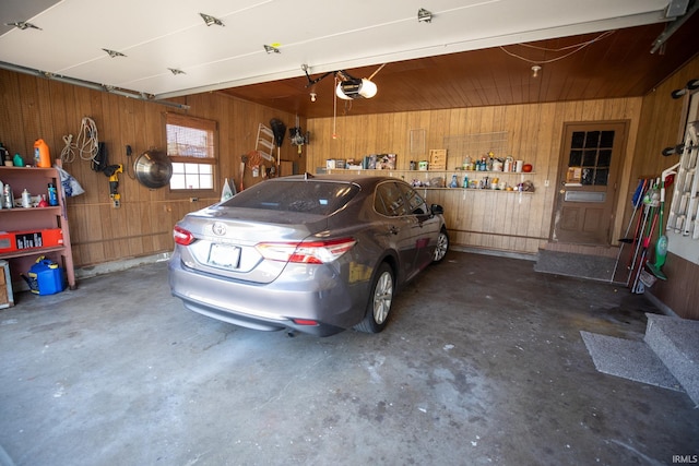 garage with a garage door opener and wood walls