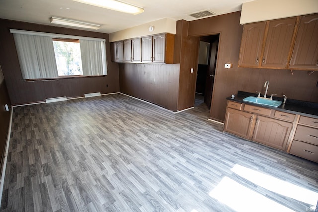 kitchen with wood-type flooring, wooden walls, and sink