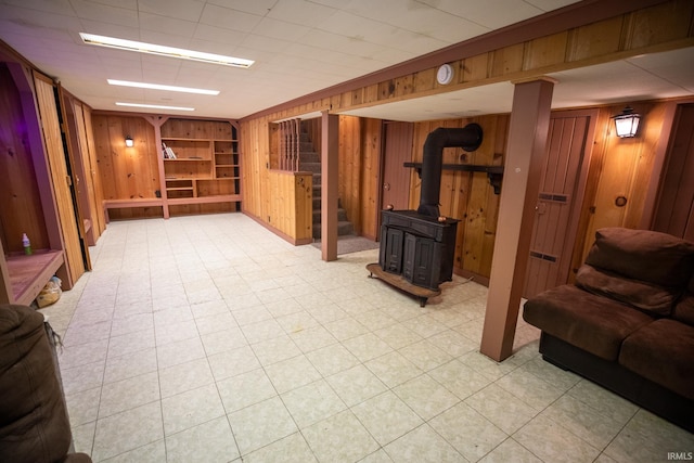 basement with built in shelves, wood walls, and a wood stove