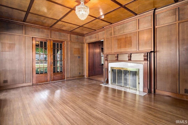 unfurnished living room featuring wood ceiling, coffered ceiling, a high end fireplace, wood-type flooring, and wooden walls