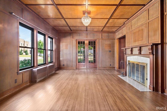 unfurnished living room featuring radiator heating unit, french doors, wooden ceiling, a fireplace, and light hardwood / wood-style floors