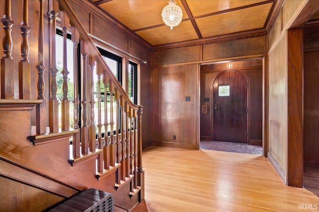 foyer featuring wood walls, light hardwood / wood-style flooring, and a chandelier