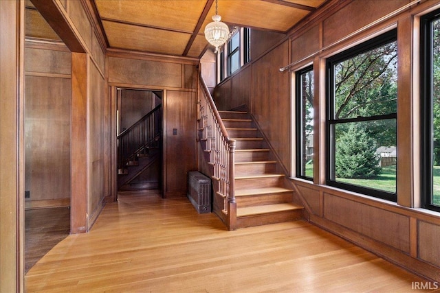 stairway with an inviting chandelier, wood walls, wooden ceiling, and hardwood / wood-style floors