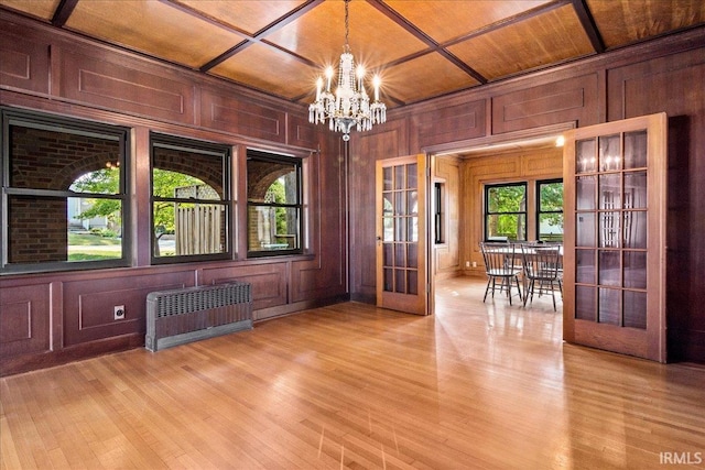 empty room featuring light hardwood / wood-style floors, coffered ceiling, wooden ceiling, radiator, and a notable chandelier