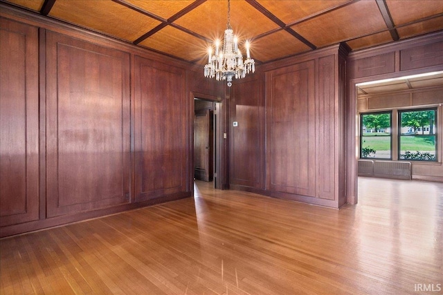 unfurnished room featuring coffered ceiling, a notable chandelier, light wood-type flooring, and wood ceiling