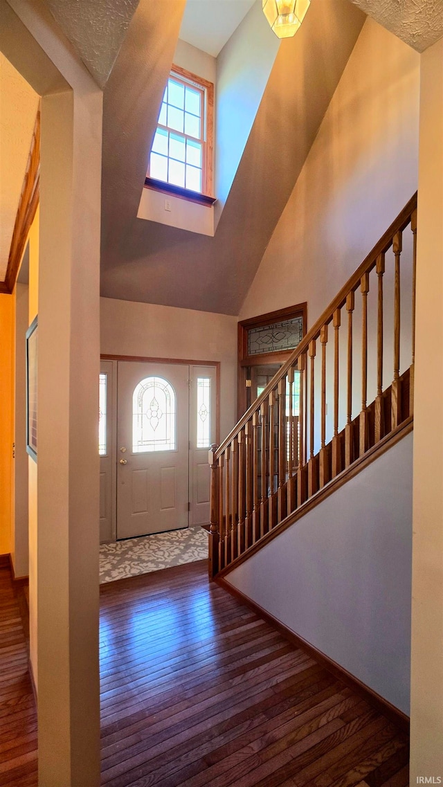 foyer entrance with a healthy amount of sunlight, dark hardwood / wood-style flooring, and high vaulted ceiling