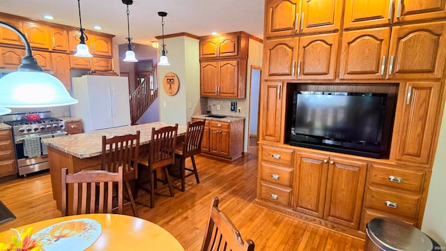 kitchen with light stone counters, pendant lighting, stainless steel stove, a center island, and white fridge